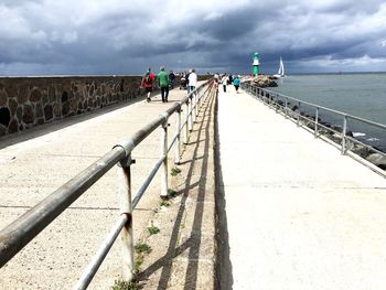 People on shore by sea against sky