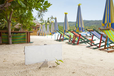 Empty chairs on beach against sky