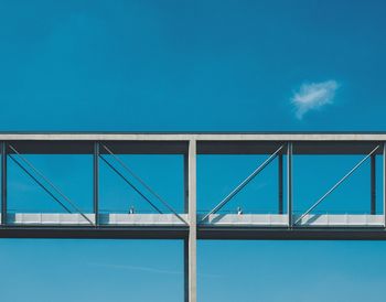 People on elevated walkway against clear blue sky