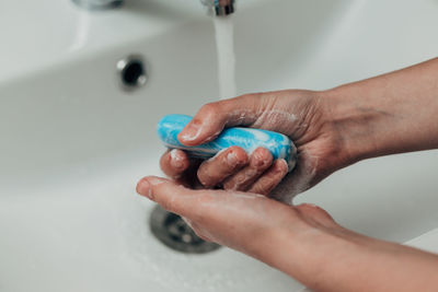 Cropped hand washing hands in sink