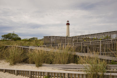 Lighthouse by building against sky