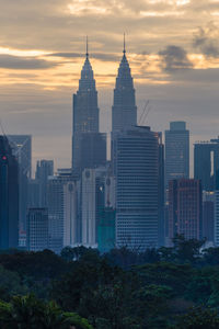 Modern buildings in city against sky during sunset