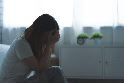 Side view of young woman sitting on sofa at home