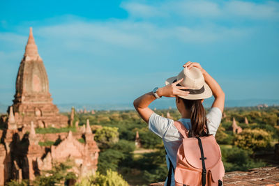 Rear view of woman wearing hat while looking at historic building