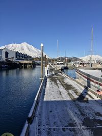 View of marina on snow covered harbor against clear blue sky