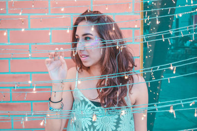 Woman standing by illuminated string lights