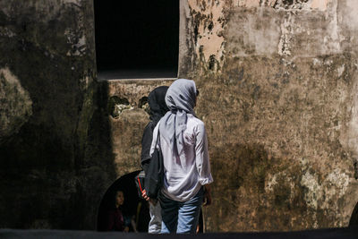 Rear view of men walking against wall