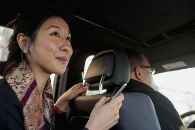 Businesswoman holding smartphone while sitting in car