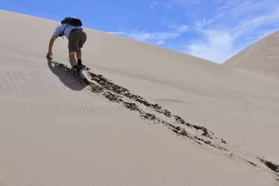 Low angle view of man climbing on sand dune at dessert