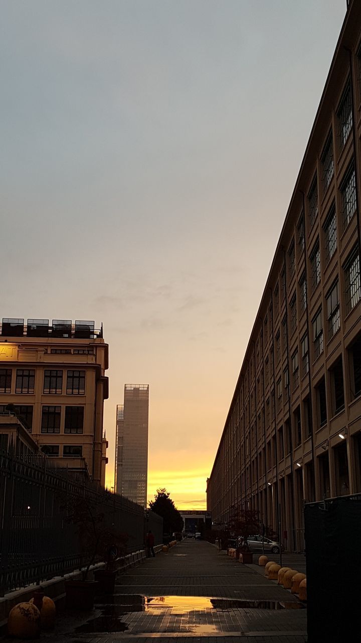 EMPTY ROAD BY BUILDINGS AGAINST SKY DURING SUNSET