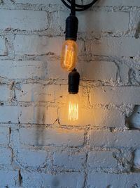 Low angle view of light bulb hanging on wall