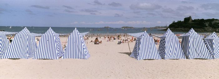 Scenic view of beach with tents against sky