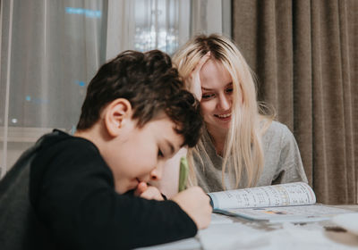 Mom and son are doing homework. sister helps brother solve math. home schooling. high quality photo