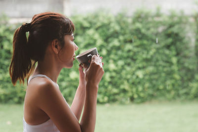 Side view of young woman using mobile phone outdoors