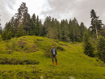 Rear view of man gesturing thumbs up while standing on grass against sky