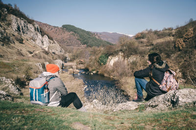 People sitting on mountain against sky