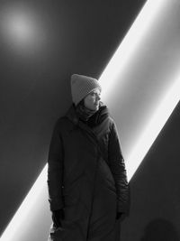 Woman standing against illuminated wall at night