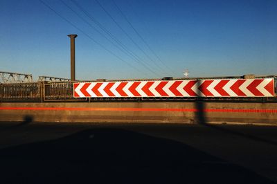 Road sign on bridge against clear blue sky