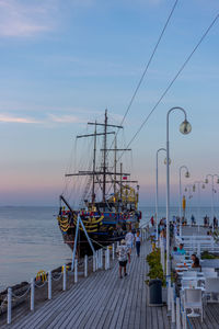 Sailboats moored at harbor against sky during sunset
