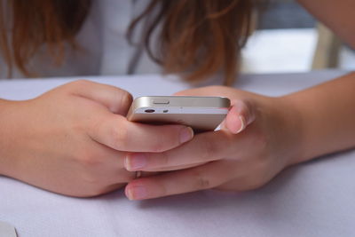 Midsection of woman using mobile phone at table