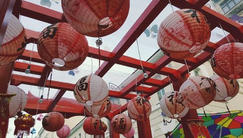 Low angle view of chinese paper lanterns hanging from red wooden structure at chinatown
