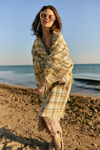 Young woman standing at beach against clear sky