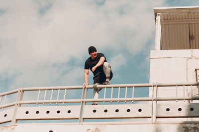 Men standing on railing against sky