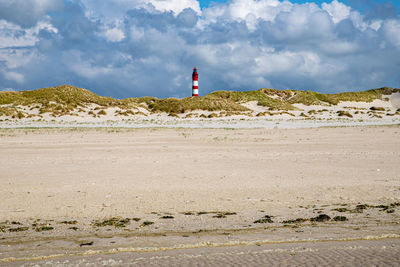 Lighthouse on beach against sky