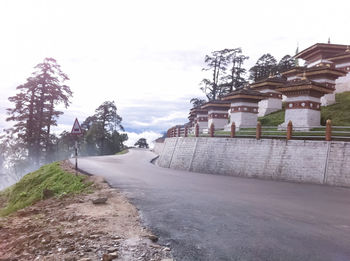 Road by built structure against sky