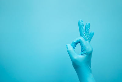 Close-up of human hand against blue background