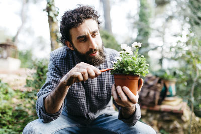 Young man sitting on potted plant