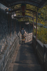 Rear view of man standing on footpath against building