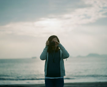 Man photographing sea against sky