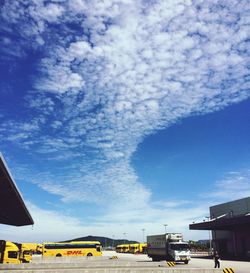 Cars on road against cloudy sky