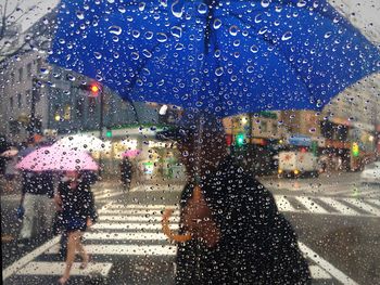 People on city street seen through glass in rains