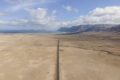 Aerial view of a straight road crossing a desert valley near caleta de famara in lanzarote, canary