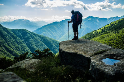 Rear view of hiker looking at mountains against sky