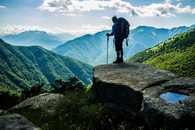 Rear view of hiker looking at mountains against sky