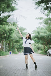 Young woman with umbrella standing on road