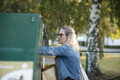 Blond woman throwing rubbish into waste bin