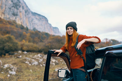 Young woman smiling while standing on car