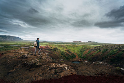 Man standing on field against cloudy sky