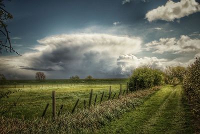 Scenic view of grassy field against cloudy sky
