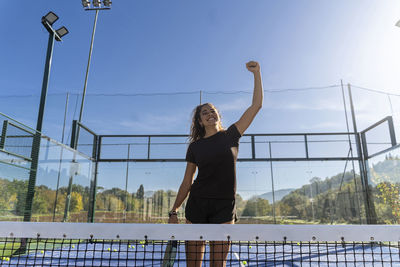 Happy young woman cheering at sports court