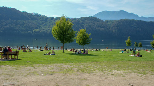 People at lakeshore against mountains