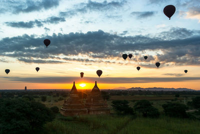 Hot air balloons in field against sky during sunset