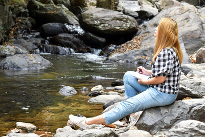 Woman sitting on rocks at shore