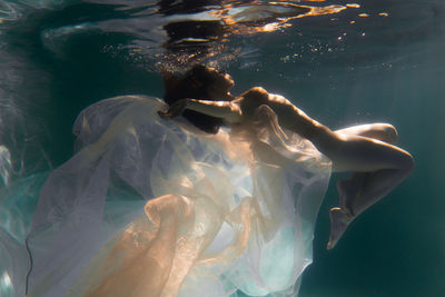 Woman with curtain swimming in pool