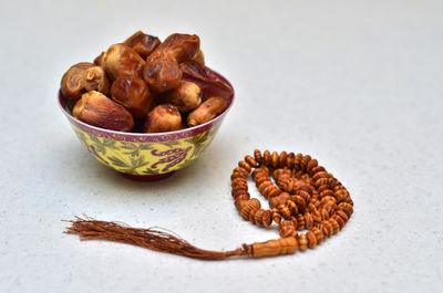 Close-up of date fruits by rosary beads in bowl