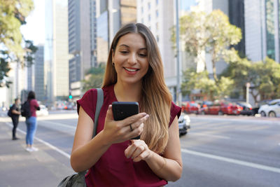 Confident businesswoman using mobile phone for internet banking on paulista avenue,sao paulo, brazil